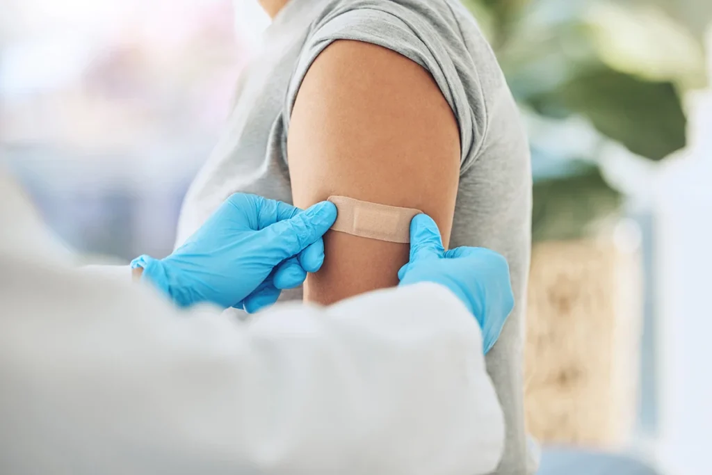 Eine Ärztin klebt ein Pflaster auf den Arm einer Patientin nach der Grippe Impfung in Wien.